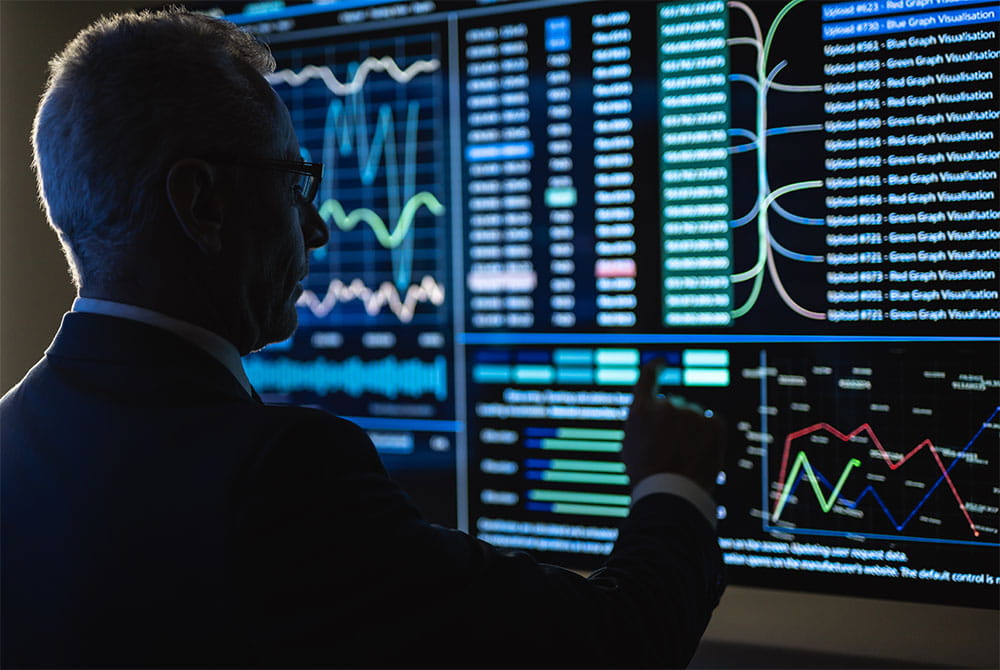adult-man-analyzes-data-on-multiple-computer-screen
